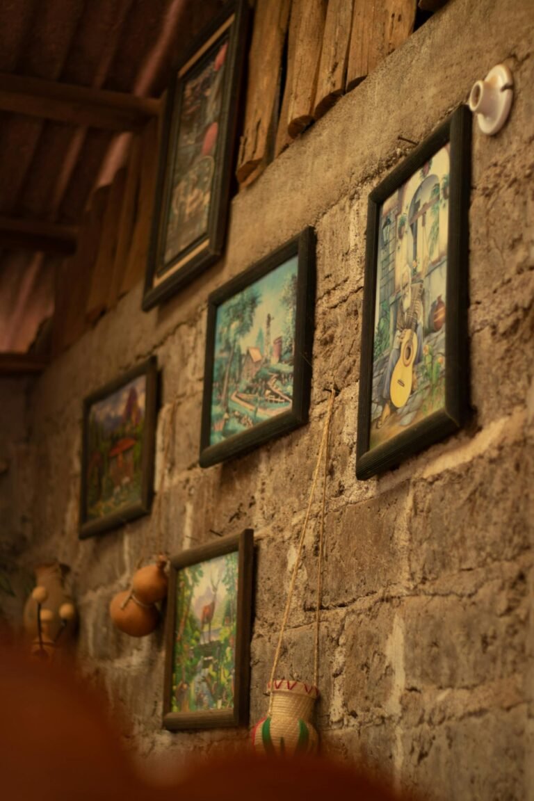 A rustic wall adorned with framed artistic paintings and traditional crafts, creating a warm vintage ambiance.