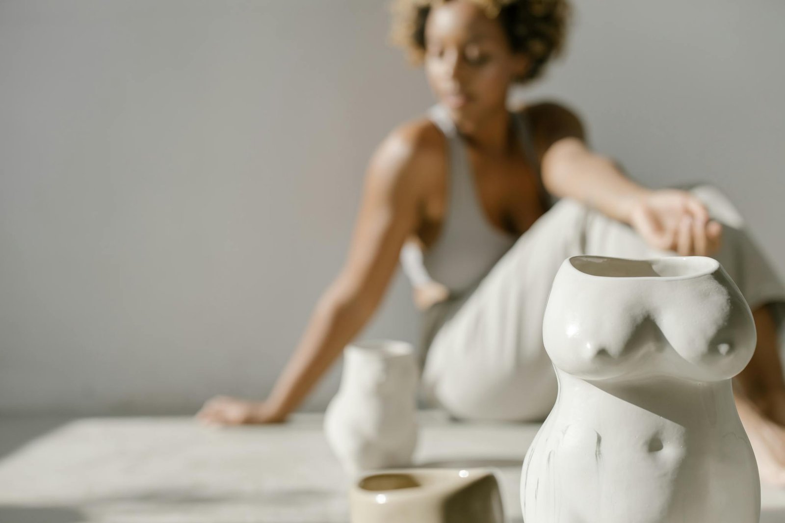 Artistic ceramic vases with human body shapes on a soft focused background.