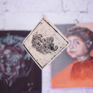 Close-up of an artistic wall hanging and paintings in a gallery, showcasing creativity.