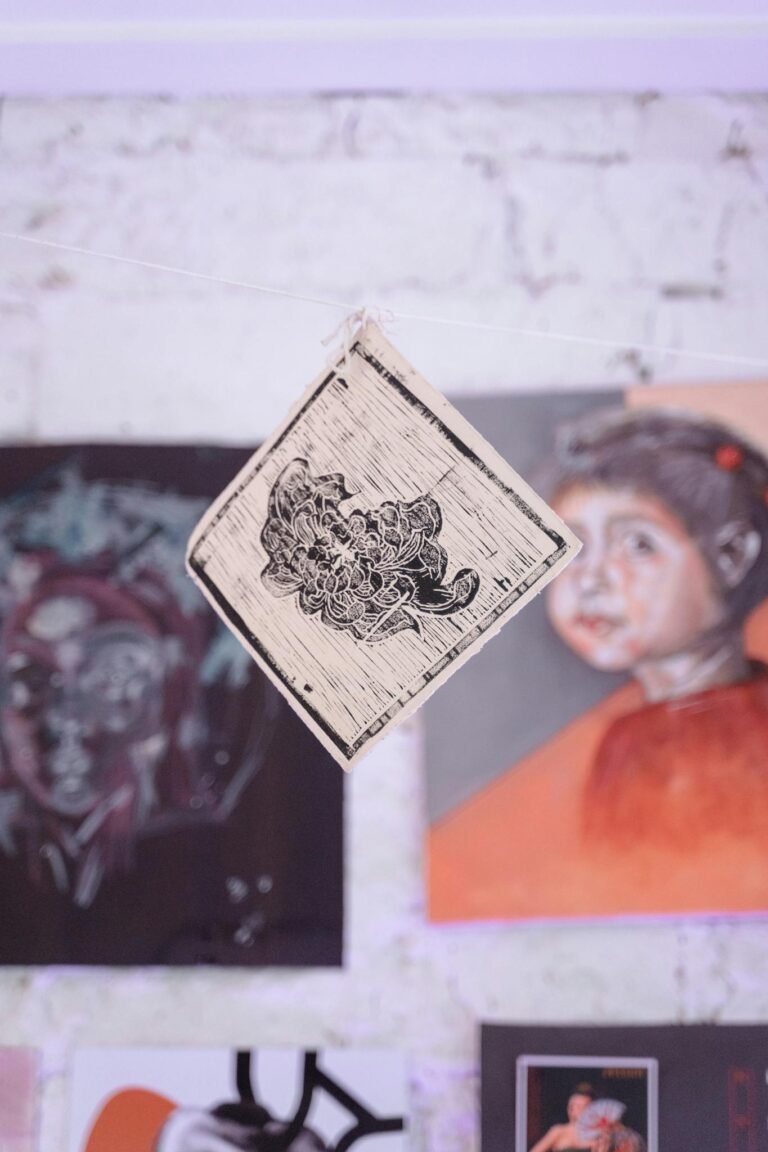 Close-up of an artistic wall hanging and paintings in a gallery, showcasing creativity.